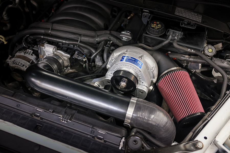 ProCharger supercharger system installed in a GM truck engine bay with polished head unit and air-to-air intercooler piping